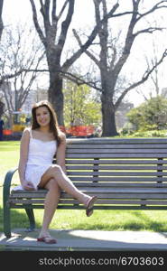 A young Australian woman in a melbourne park, sitting on a bench sunny and fresh.