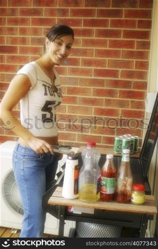 A young Australian woman on her balcony is preparing a typical barber que.