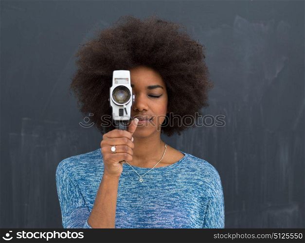A young beautiful african american woman using a retro video camera isolated on a gray background
