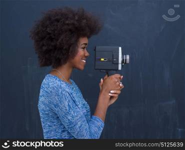 A young beautiful african american woman using a retro video camera isolated on a gray background