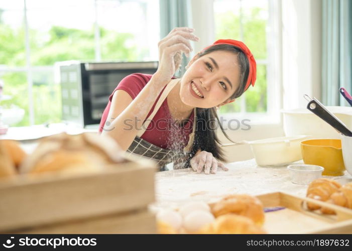 A young beautiful Asian woman is baking in her kitchen , bakery and coffee shop business