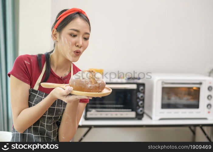 A young beautiful Asian woman is baking in her kitchen , bakery and coffee shop business