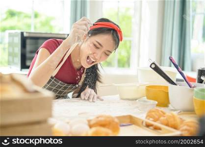A young beautiful Asian woman is baking in her kitchen , bakery and coffee shop business