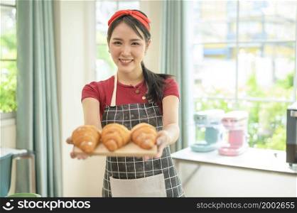 A young beautiful Asian woman is baking in her kitchen , bakery and coffee shop business