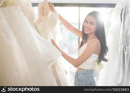 A young beautiful bride choosing a wedding outfit at wedding studio, marriage concept.   . Young beautiful bride choosing a wedding outfit at wedding studio, marriage concept.   