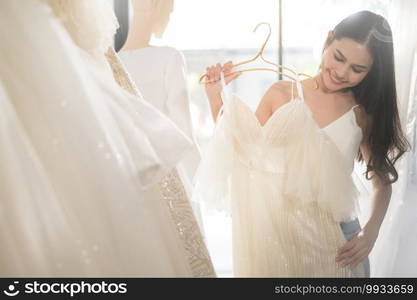 A young beautiful bride choosing a wedding outfit at wedding studio, marriage concept.   . Young beautiful bride choosing a wedding outfit at wedding studio, marriage concept.   