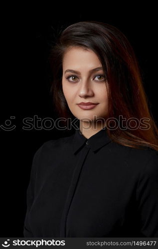 a young beautiful Muslim woman with brown hair in a black blouse and black leather skirt on a black isolated background