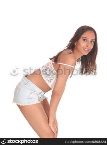 A young beautiful woman in shorts and brunette hair standing in profile and bending forwards, smiling, isolated for white background