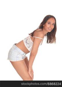 A young beautiful woman in shorts and brunette hair standing in profile and bending forwards, smiling, isolated for white background