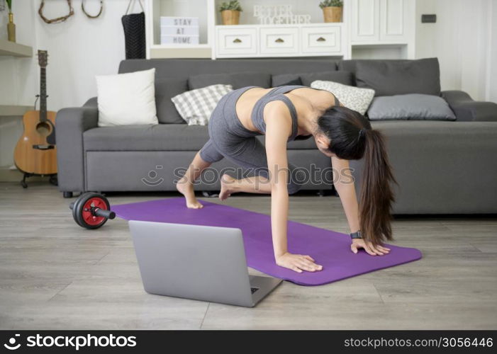 A Young beautiful woman is doing the mountain climber exercise at home