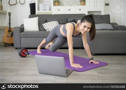 A Young beautiful woman is doing the mountain climber exercise at home