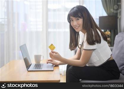 A young beautiful woman is using credit card for online shopping on internet website at home, e-commerce concept. Young beautiful woman is using credit card for online shopping on internet website at home, e-commerce concept