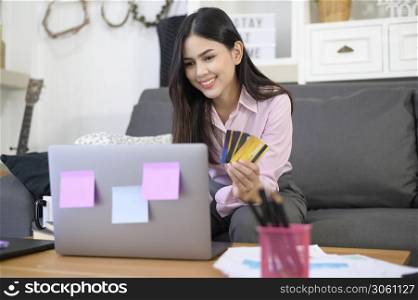 a young beautiful woman is using credit card for online shopping on internet website at home, e-commerce concept