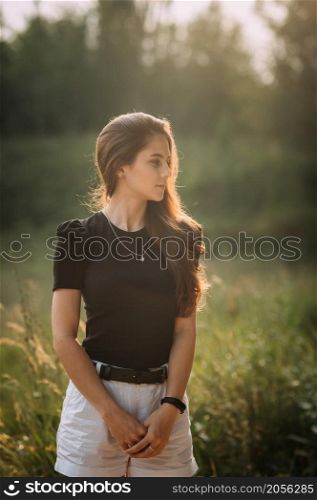 A young beauty walks under the rays of the summer sun in the meadows of the undergrowth.. A joyful beauty walks in the rays of the setting sun in nature 3663.