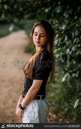 A young beauty walks under the rays of the summer sun in the meadows of the undergrowth.. A joyful beauty walks in the rays of the setting sun in nature 3665.