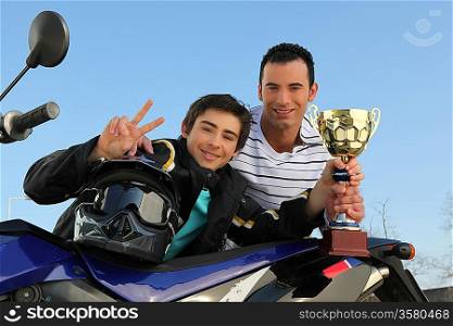 A young biker with a trophy.