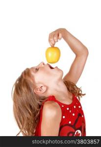 A young blond girl is playing with her yellow apple she likes to eat,isolated on white background.