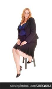 A young blond plus size woman in a black skirt and jacket and corset, sitting on a chair isolated for white background.