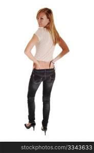 A young blond red haired woman in gray jeans and a beige sweaterstanding from the back and looking over her shoulder, for white background.
