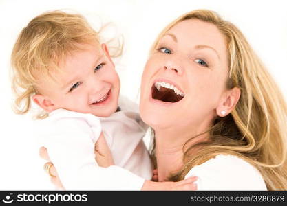 A young blonde mother and her son dressed in white and having laughing together