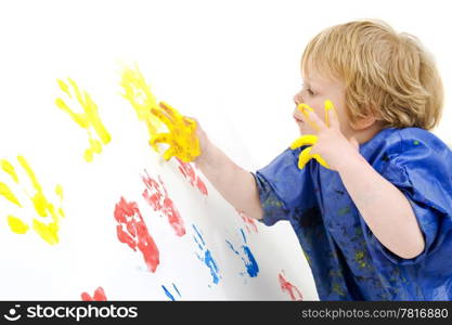 A young boy, attentively working on a finger painted painting on a wall