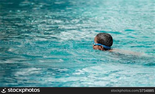 A young boy doing his laps in a swimming pool