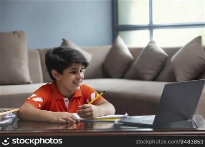 A YOUNG BOY HAPPILY ATTENDING ONLINE CLASS AT HOME