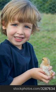 A young boy holds a little chick