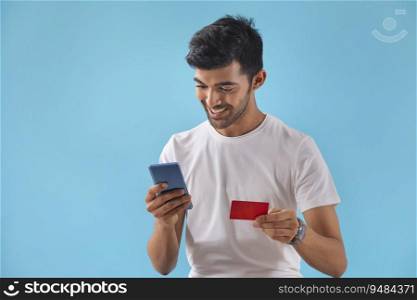 A young boy looking at his credit card and mobile phone. 
