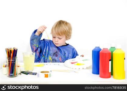 A young boy making a painting with poster paint