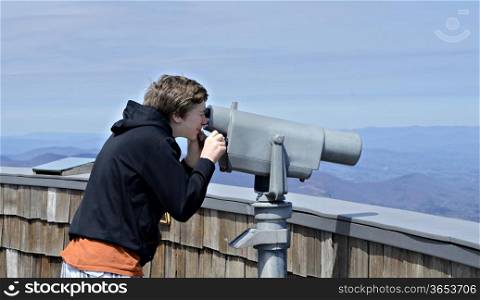A young boy on Brasstown Bald looking at the view with a telescope.