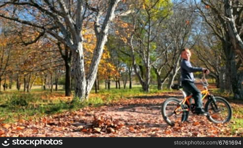 A young boy races through the park on his bike.