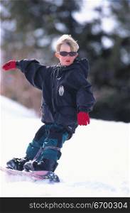 A young boy snowboarding down a slope