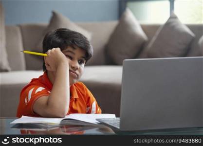 A YOUNG BOY TRYING TO CONCENTRATE DURING ONLINE CLASS