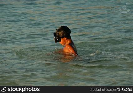 A young boy wearing scuba goggles in water, Moorea, Tahiti, French Polynesia, South Pacific