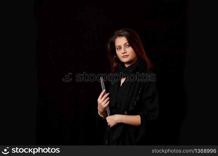 a young brown-haired girl in black clothes with a laptop in her hands. on a black isolated background.