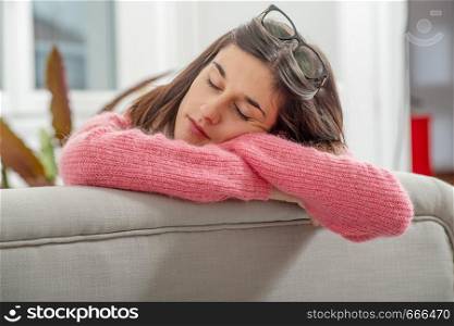 a young brunette woman with pink sweater resting on the sofa