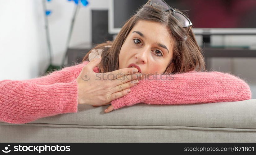 a young brunette woman with pink sweater resting on the sofa