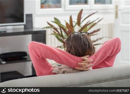 a young brunette woman with pink sweater resting on the sofa