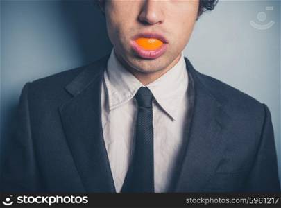 A young businesman is posing with an orange peel in his mouth