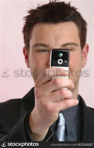 A young business man takes a photo with his mobile phone.