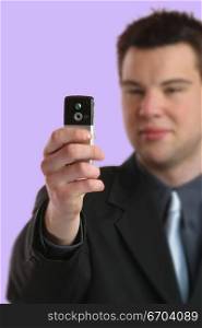 A young business man takes a photo with his mobile phone.