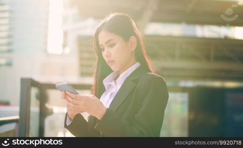 A young business woman wearing black suit is using smart phone , in the city, Business Lifestyle Concept. 