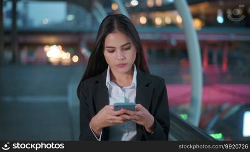 A young business woman wearing black suit is using smart phone , in the city, Business Lifestyle Concept. 