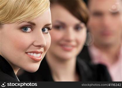 A young (business) woman with her colleagues or frinds out of focus behind her