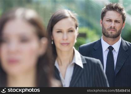 A young businessman business man with beard waiting behind two businesswomen in line