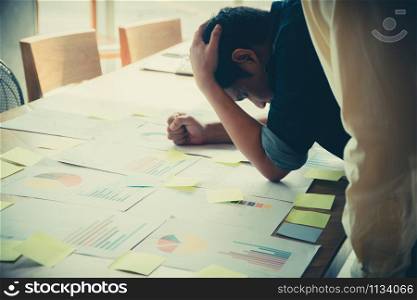 A young businessman holds his head in the head due to disappointment. From operating results with loss. The concept of the mistake of doing business is wrong due to a lack of experience.