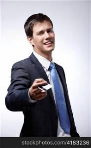 A young businessman holds out a credit card