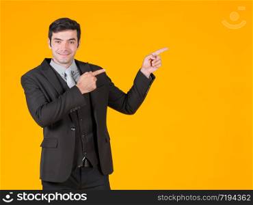 A young businessman in a gray shirt and a black suit pointing both finger in the same direction. Shows the project that is currently soaring. The concept of investing in a successful business.
