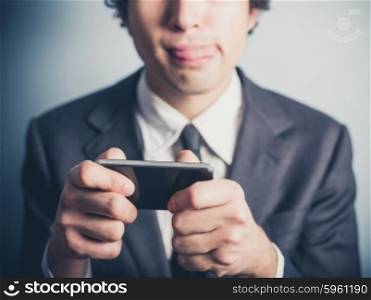 A young businessman is playing mobile games on his smartphone